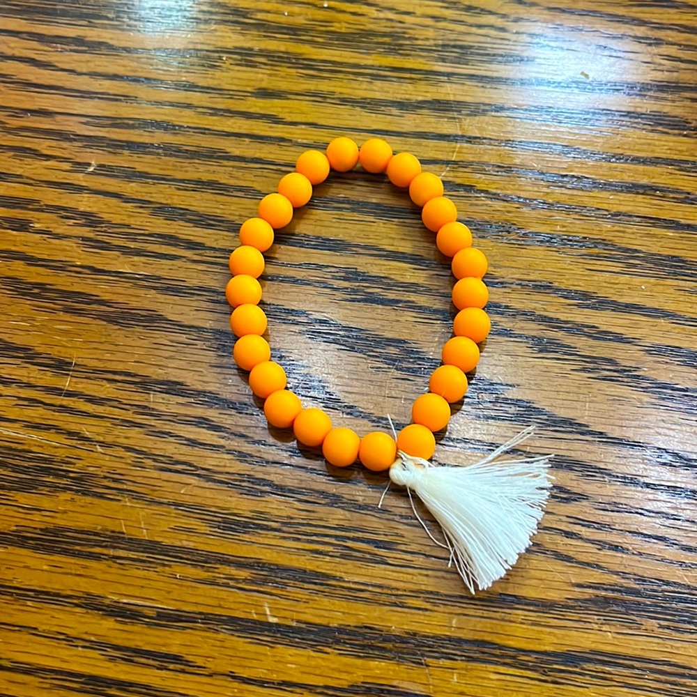 I am selling this beautiful bracelet. It is orange and has white little strings